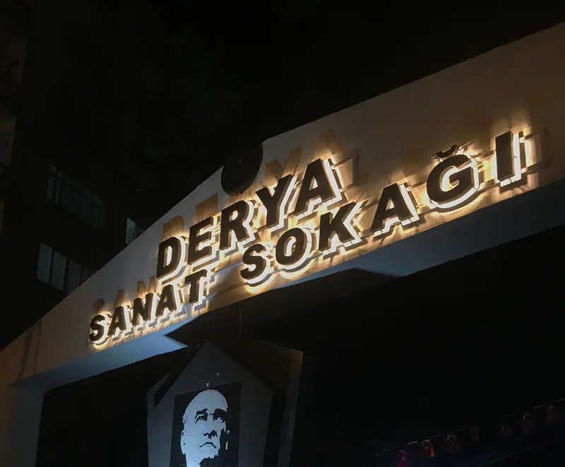 Arkadan aydınlatmalı harflerin duvarda bıraktığı yumuşak ışık halesi, gece görünümü