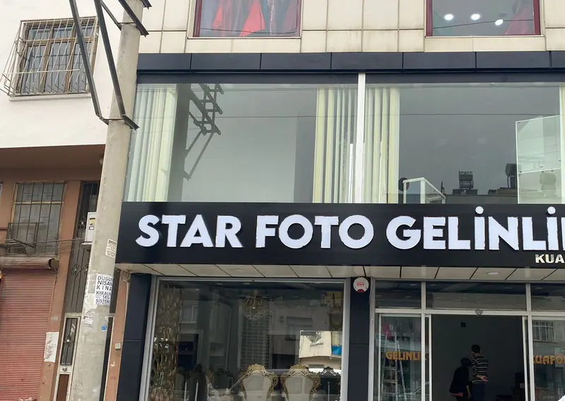 Siyah kompozit alın üzerine beyaz kutu harfler, dükkân cephesi gündüz görünümü
