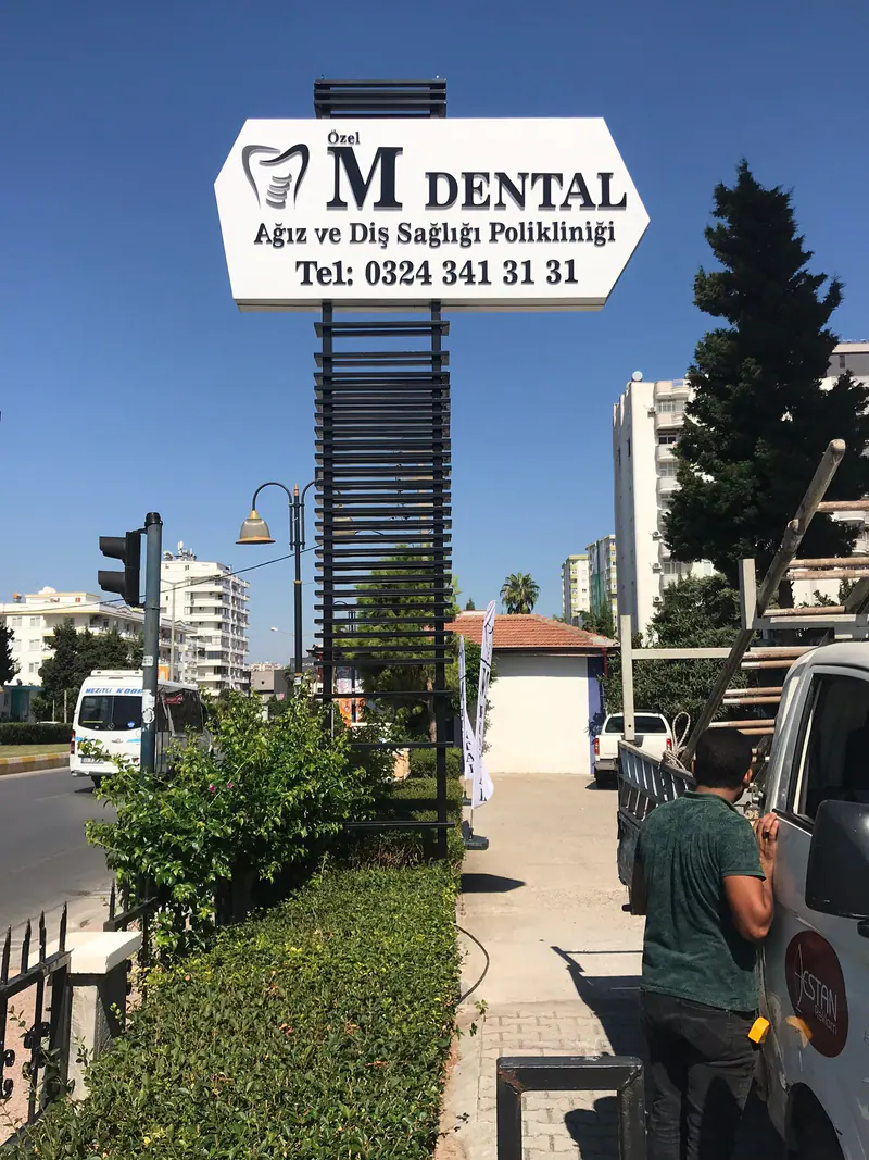 Bina girişinde çok bölmeli yön ve totem tabelası, yanında Destan Reklam servis aracı